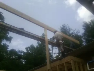 Carpenter setting a ridge beam over a new addition frame — Ice Dam Removal by Roofing Brothers in College Corner