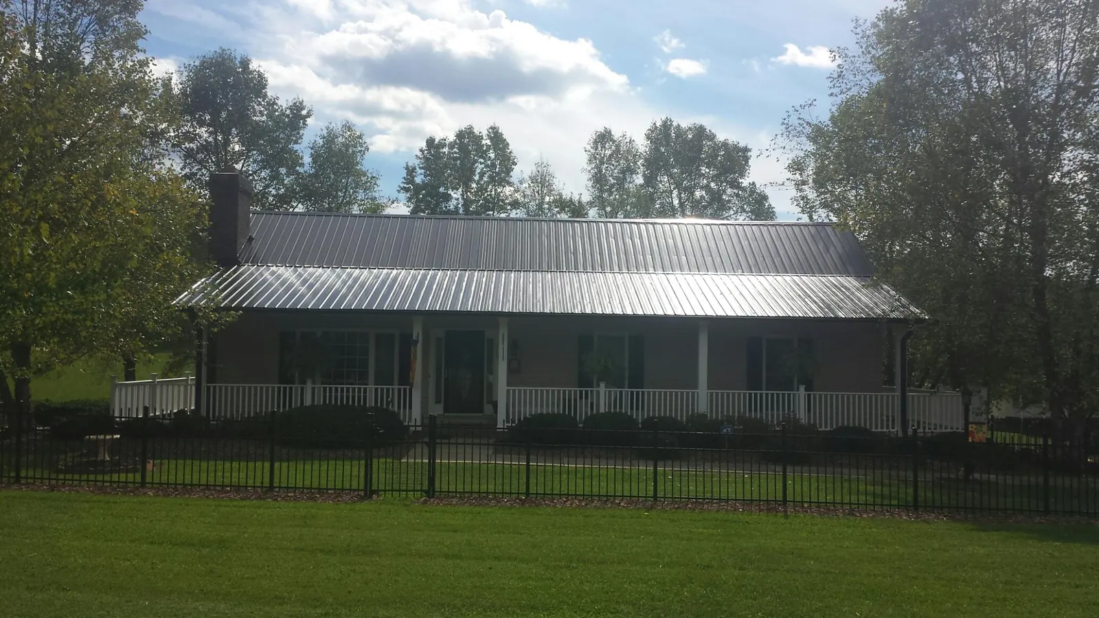 Gray metal roof on a brick ranch with a full width front porch — Gutter Guard Installation work by our crew in College Corner