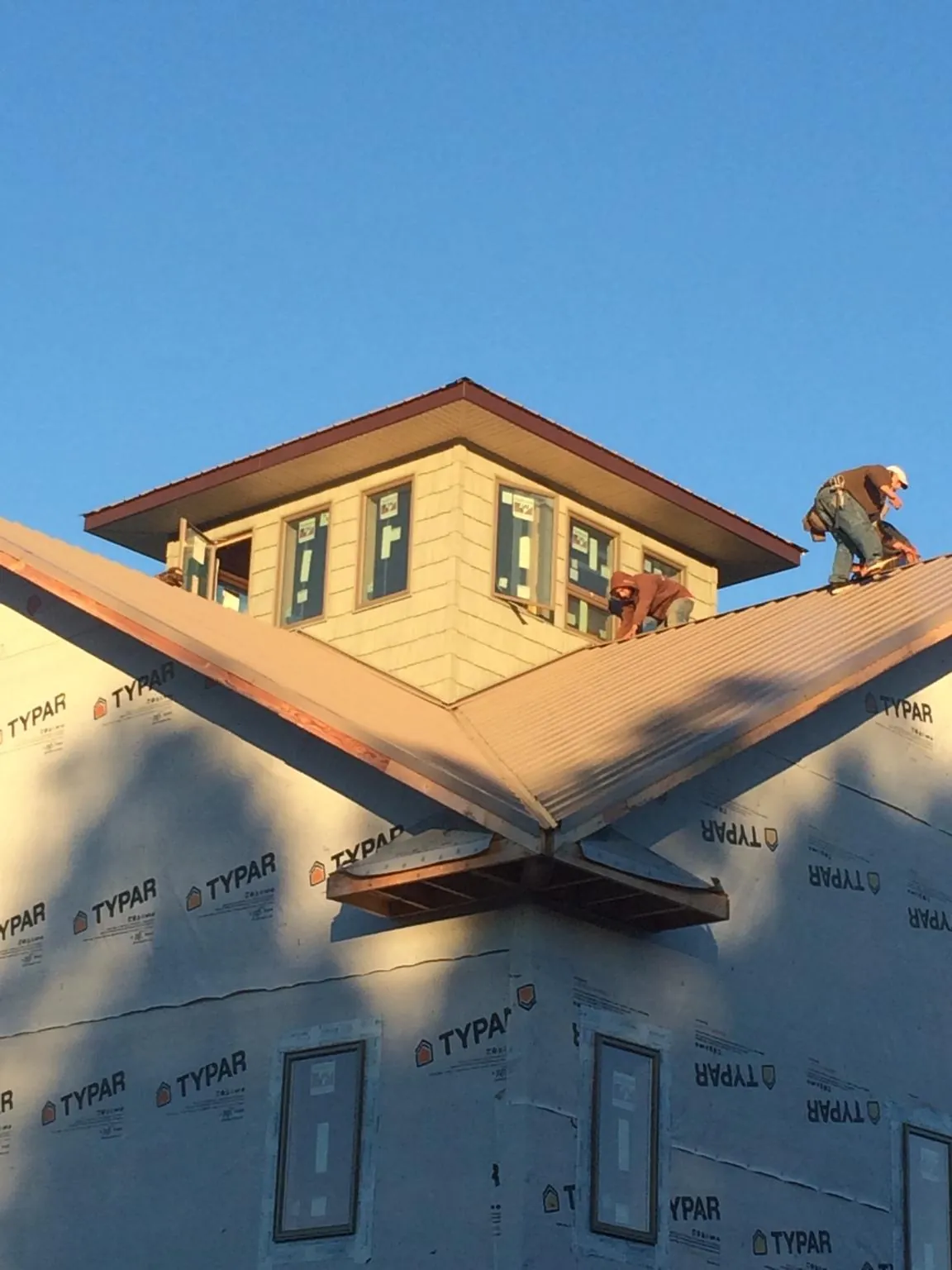 Roofers working around a rooftop cupola on a new metal roof at sunset — Roof Waterproofing in College Corner by Roofing Brothers